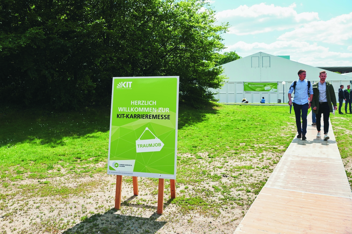 Grünes Wegschild vor dem Zelt der KIT-Karrieremesse