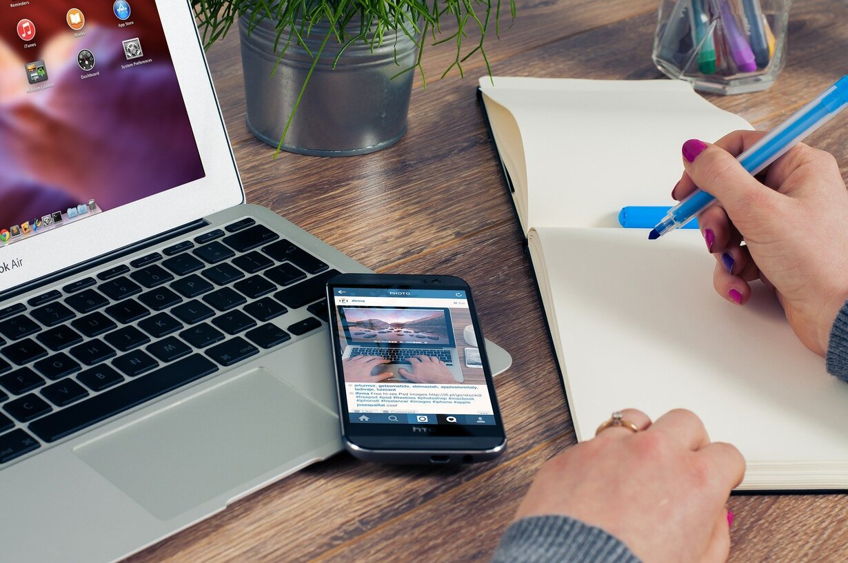 Frauenhand mit Stift, PC und Handy